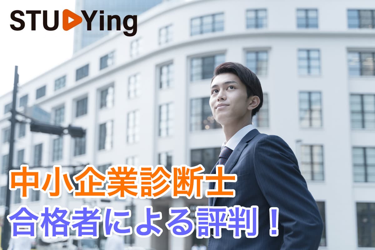 白い低層ビルの手前でポーズをとるスーツ姿の若い男性